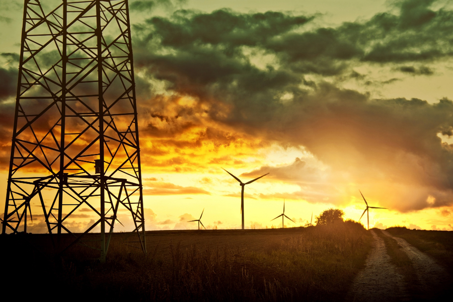zachód słońca, a na jego tle wiatrak oraz słup wysokiego napięcia (branża energetyczna i SCADA)