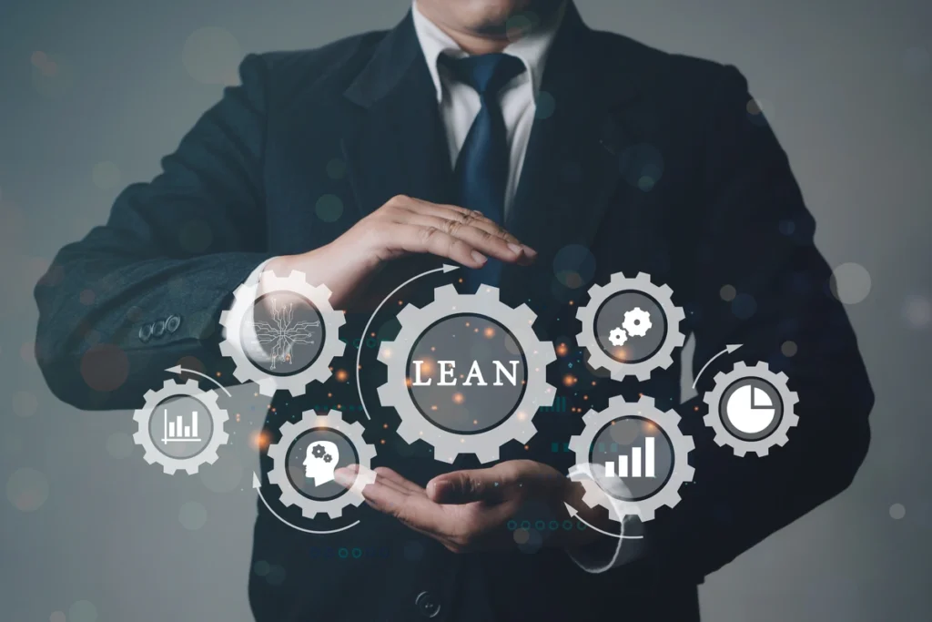 Lean manufacturing (popiersie mężczyzny w garniturze, przed którym widać zębatki z ikonami i napisem Lean)