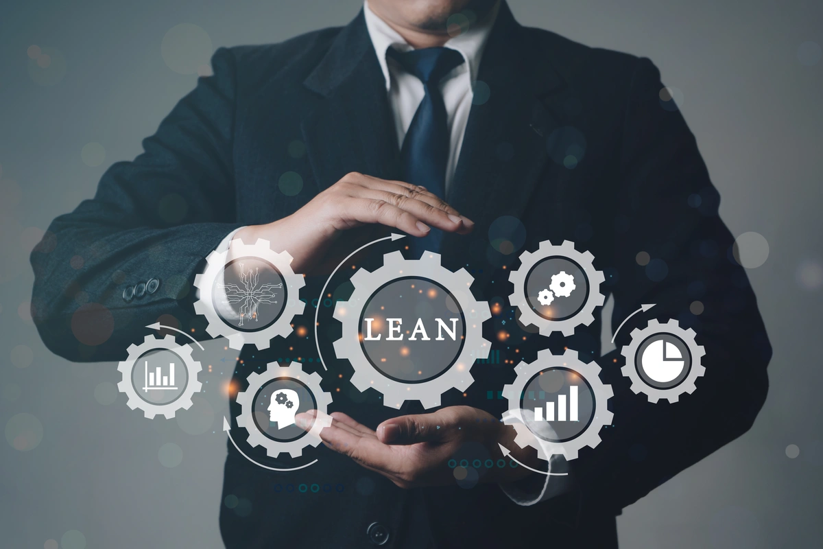 Lean manufacturing (popiersie mężczyzny w garniturze, przed którym widać zębatki z ikonami i napisem Lean)