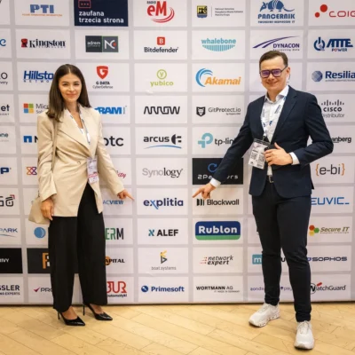 Kasia Kowalska i Adrian Stelmach na tle ścianki z logo explitia (konferencja o cyberbezpieczeństwie)