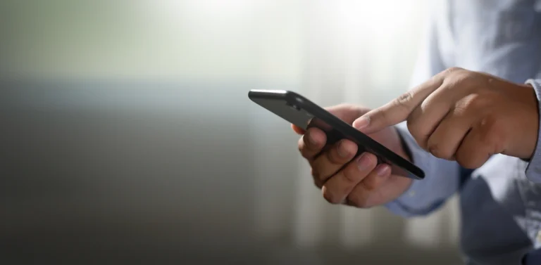 system powiadomień sms (iPhone w ręku mężczyzny w koszuli)