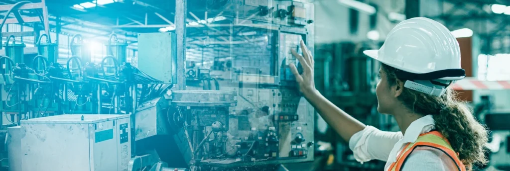 mikroprzestoje w produkcji (kobieta w białym kasku stoi przed maszyną na produkcji)