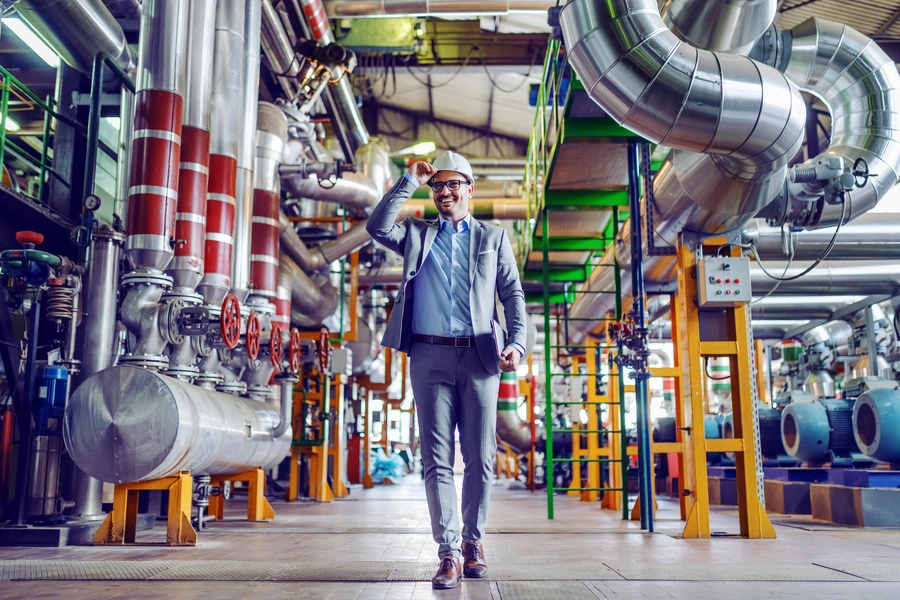 cyfryzacja a Przemysł 4.0 (mężczyzna w garniturze i białym kasku idzie przez halę produkcyjną)